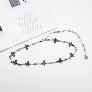 Close-up of butterfly waist chain with black inlay and rose pendant on silver metal link