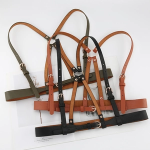 Three colors of faux leather body harnesses with gold buckles on a fashion magazine