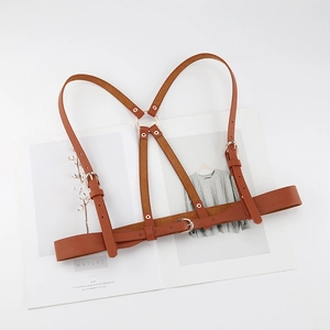 Brown leather body harness with gold metal buckles on a minimalist background