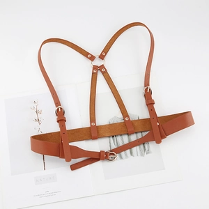 Detail of adjustable brown leather harness vest featuring golden metal buckles and Y-back ring
