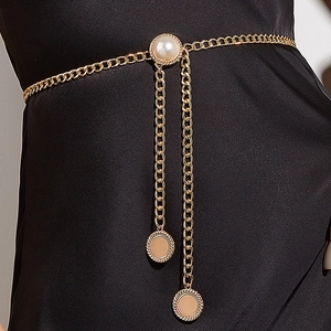 Close-up of golden waist chain featuring a large pearl and dangling metal pendants