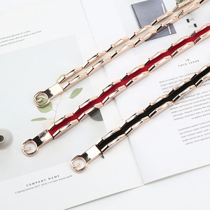 Close-up of thin elastic waist belts with gold geometric metal buckles in black red and white