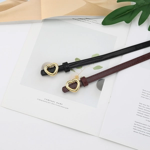 Détail de ceintures fines noires et bordeaux avec boucles coeur dorées sur des magazines