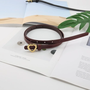 Ceinture femme en cuir bordeaux avec boucle cœur dorée présentée sur un magazine
