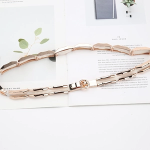 Detail showing elastic dress belt with rose gold geometric metal pieces and round hook buckle