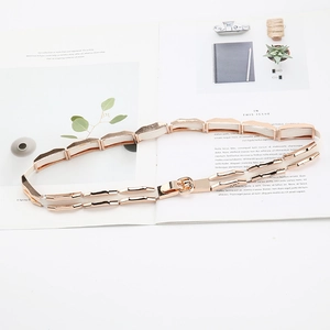 Detailed view of elastic rose gold metal waist belt on a fashion magazine background