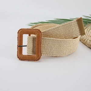 Detail of beige woven straw belt with rectangular resin buckle and palm leaf background