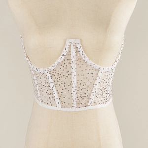 Détail du haut corset blanc orné de sequins champagne avec une structure à baleines