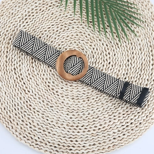 Detail of woven elastic belt with geometric patterns and solid round wooden buckle