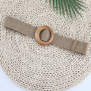 Straw woven belt for women with round wooden buckle on a natural fiber mat