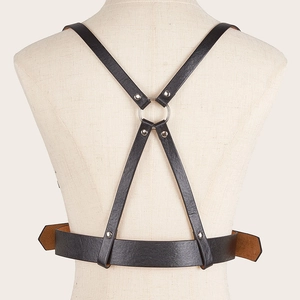 Detail of punk style leather body harness with X-shaped back and silver metal rings