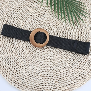 Detail of black woven elastic belt for women with a round wooden buckle and leather tip