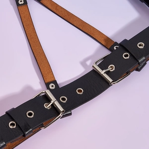 Detail of black leather punk harness featuring silver buckles and tan suede lining