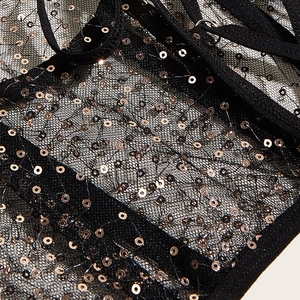 Gros plan détaillé sur un tissu en maille noire orné de paillettes or rose élégantes