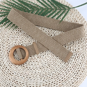 Detail of woven straw belt for women with round wooden buckle on decorative palm leaf