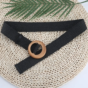 Women's black woven straw belt featuring a round wooden buckle on a natural palm background