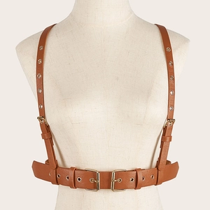 Détail du harnais en cuir marron montrant les boucles dorées et les œillets métalliques
