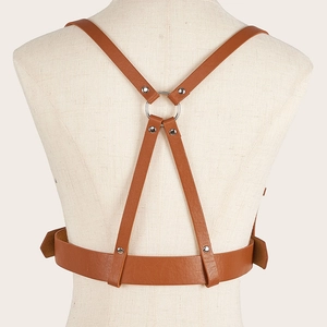 Detail of the X-shaped brown faux leather body harness with silver metal ring on the back