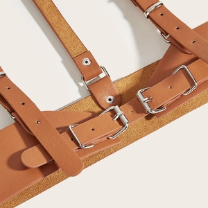 Detailed close-up of brown faux leather body harness with adjustable silver metal buckles
