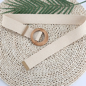 Close-up of a beige elastic woven belt with a round wooden buckle and leather trim detail