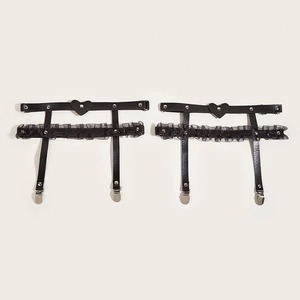 Close-up of black lace and leather thigh garters with heart rivets and metal clips