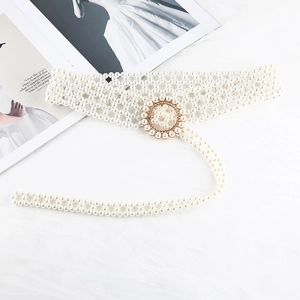 Detail of woven pearl stretch belt with golden circular buckle and stylish tassel