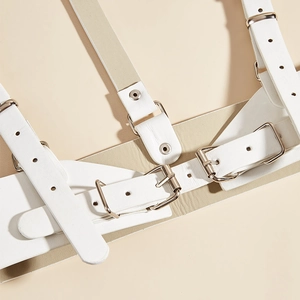 Detail of white leather body harness featuring silver metal buckles and refined rivet details
