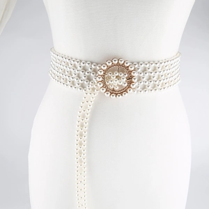 Detailed macro view of woven white pearls and vintage gold buckle on elastic belt