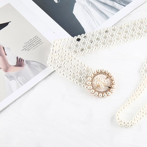 Detailed view of women's pearl beaded waist belt with elegant gold metal buckle