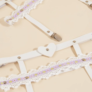 Close-up of white lace leg garter with floral embroidery and heart leather detail