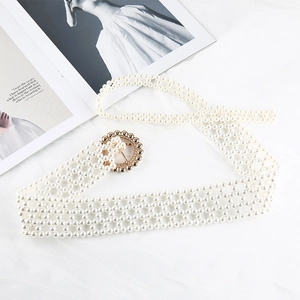 Detailed view of woven faux pearl belt with a round golden buckle on a white surface