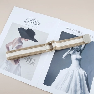 Detail view of khaki striped canvas belt with cream D-ring buckle on fashion magazine