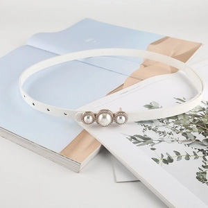 Détail d'une ceinture blanche fine avec boucle à perles élégante et strass brillants