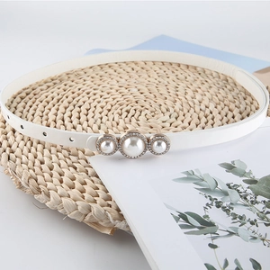 Ceinture fine en cuir blanc avec boucle en perles et strass sur fond naturel
