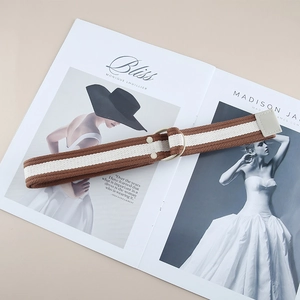 Close-up of brown and white striped canvas belt with round buckle on fashion magazine