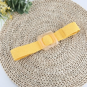 Ceinture tressée jaune élastique avec boucle carrée en résine sur tapis de paille