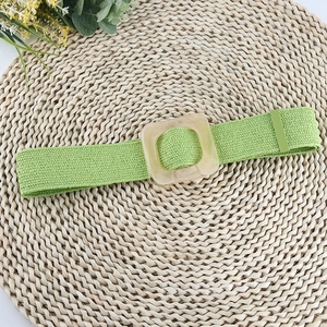 Détail d'une ceinture tressée élastique vert clair avec boucle carrée dépolie