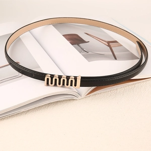 Ceinture fine en cuir noir pour femme avec boucle dorée ondulée élégante sur un magazine