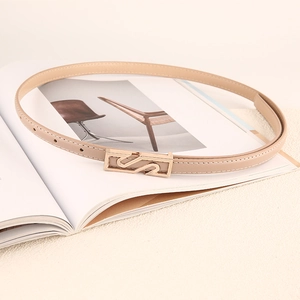 Cintura sottile in pelle beige minimalista con fibbia geometrica dorata su una rivista