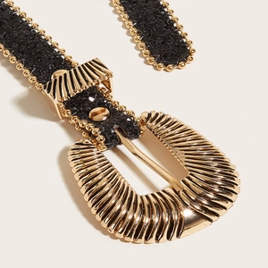 Détail de la boucle dorée vintage avec ceinture pailletée noire et perles dorées