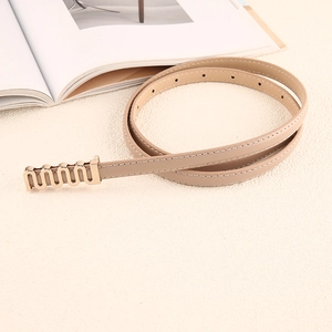 Détail de la ceinture fine en similicuir beige avec boucle dorée ondulée et couture