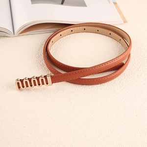 Détail d'une fine ceinture en cuir marron avec boucle dorée ondulée sur fond épuré