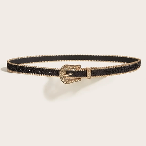 Gros plan détaillé sur la boucle dorée gravée de fleurs sur une ceinture noire pailletée
