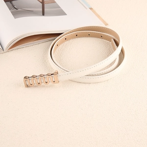 Détail d'une ceinture en cuir blanc pour femme avec boucle dorée ondulée sur fond beige