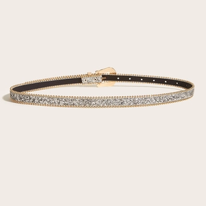 Détail de la ceinture fine argentée pailletée avec boucle fer à cheval et perles dorées