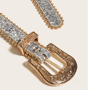 Vue détaillée de la boucle dorée gravée avec des paillettes argentées sur la ceinture