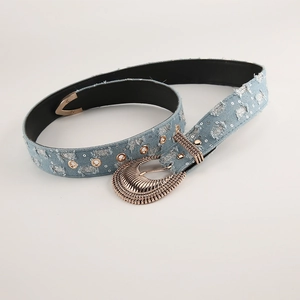 Dettaglio cintura in denim azzurro con paillettes, strappi e fibbia floreale vintage