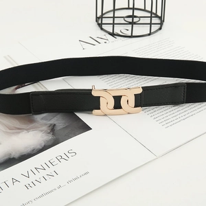 Ceinture élastique noire pour femme avec boucle en métal doré posée sur un magazine de mode