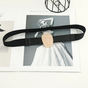 Chic black elastic waist belt with modern gold abstract face buckle on a white surface
