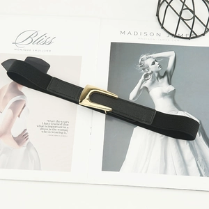 Elastic black waist belt for women with golden U-shaped buckle on a fashion magazine